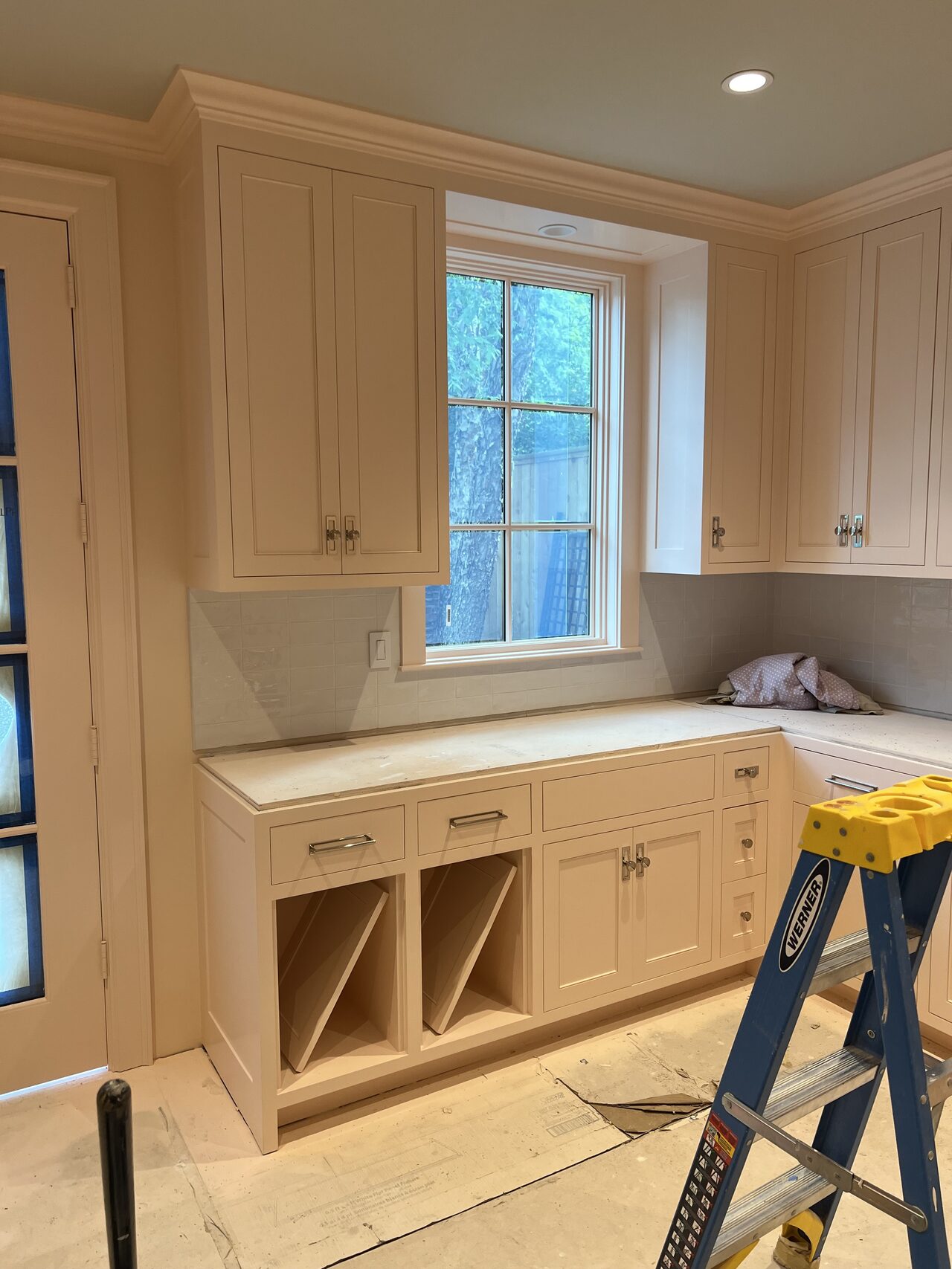 Window wall cabinet run showing drawers, open cubbies, and upper storage during installation for a Joel Hodge project.