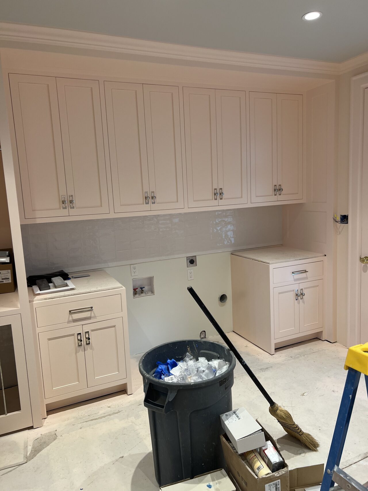 Long white built-in wall with hardware installed and protective floor covering still in place for a Joel Hodge project.