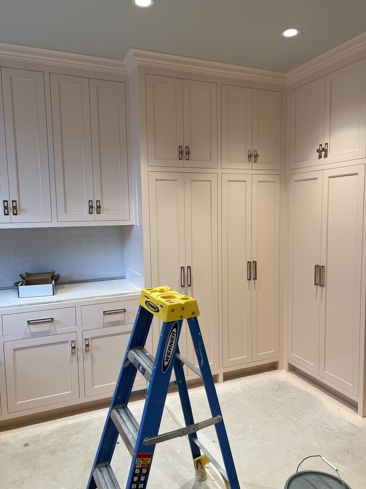 White cabinet wall reviewed around the ladder position for reveal alignment and hardware consistency for a Joel Hodge project.