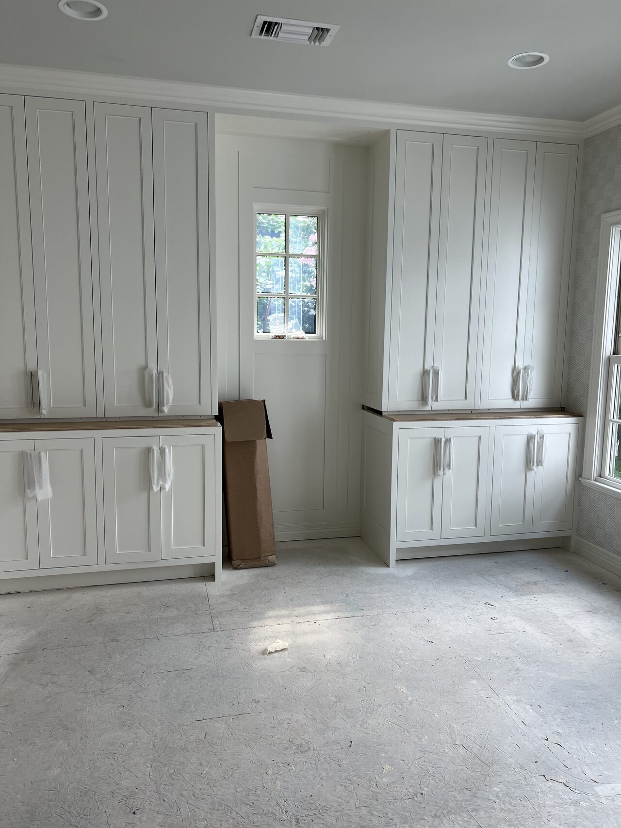 Built-in cabinet wall before final cleanup, with drawers, upper cabinets, and open center area visible for a Joel Hodge project.