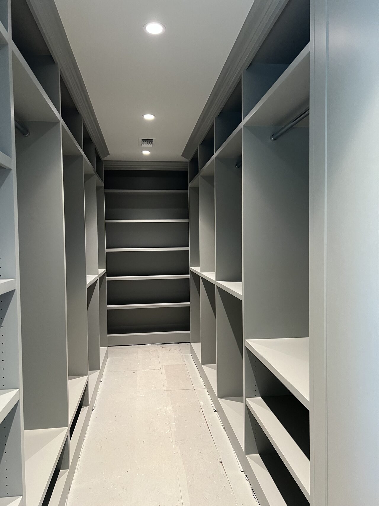 Finished walk-in closet shelving and drawer system with dark paint and integrated lighting for a Joel Hodge project.