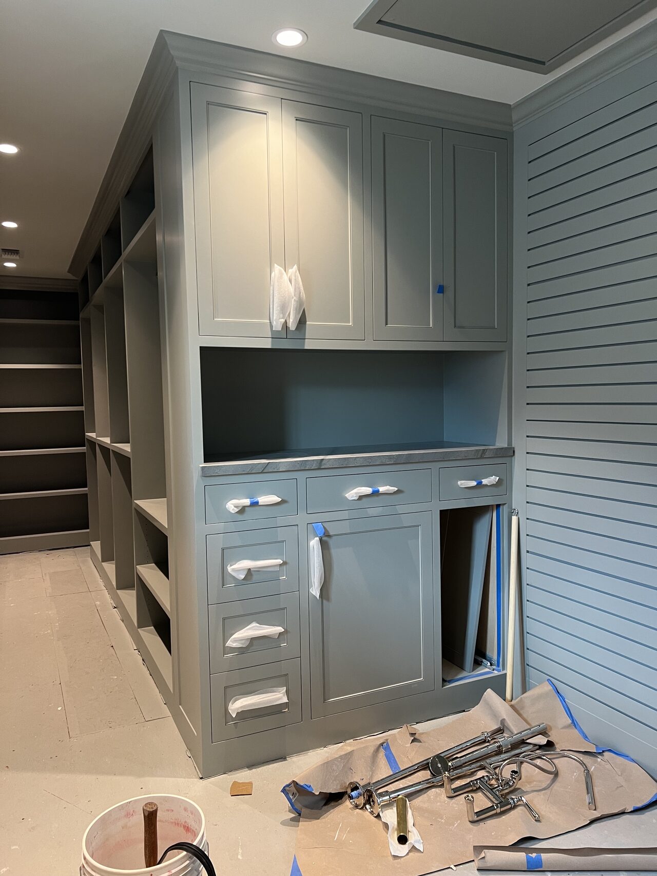 Blue built-in cabinet unit with drawers, upper storage, and lit display niche during final setup for a Joel Hodge project.