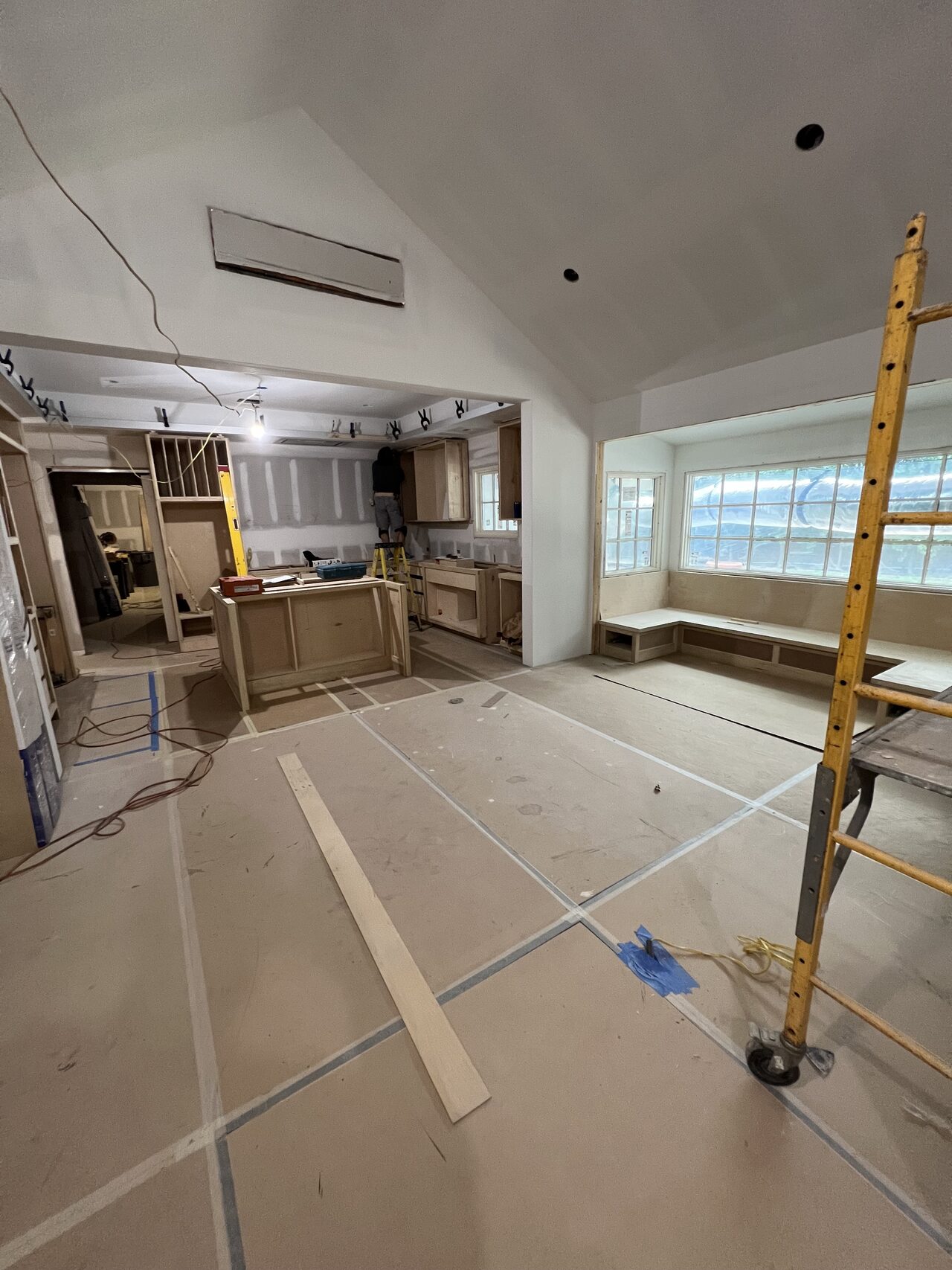 Room-side view of the built-in work area with ladder and cabinet parts staged for trim installation for a Joel Hodge project.